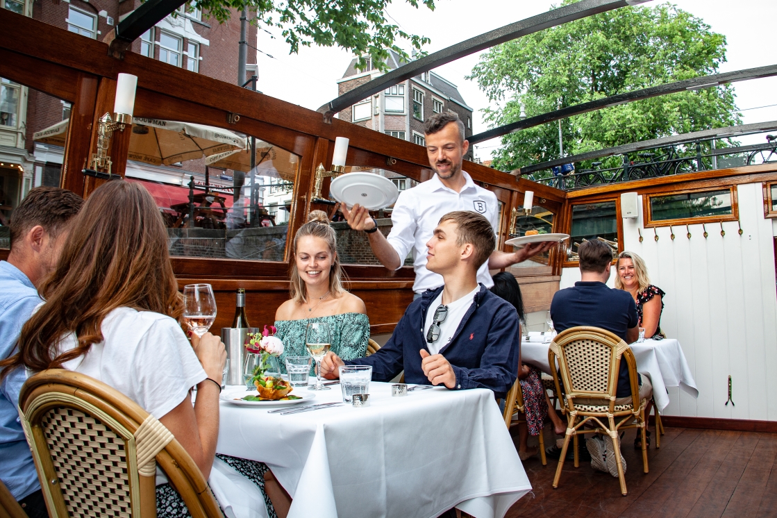 Blij gezelschap geniet van de luxury dinner cruise op de Amsterdamse grachten.